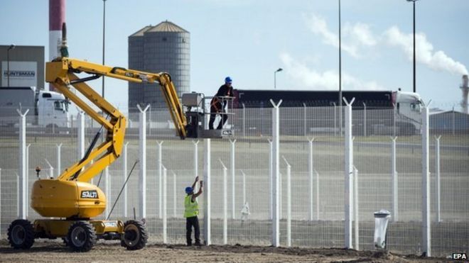 Рабочие строят высокий забор возле порта Кале