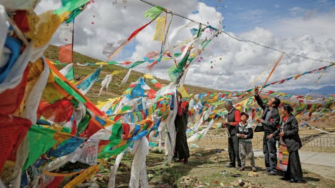 Creyentes budistas colgando banderas de oración en un cruce montañoso