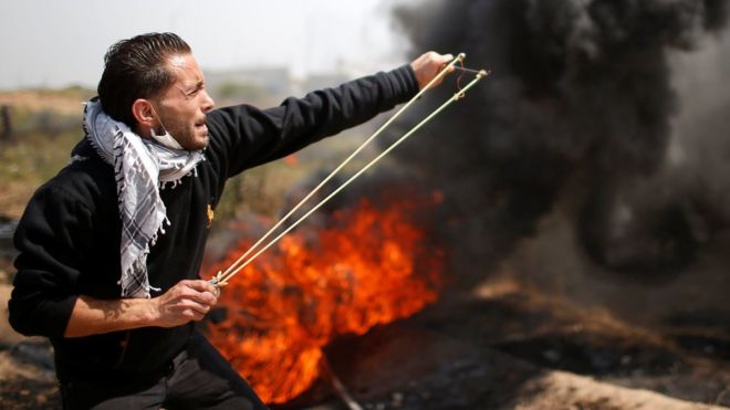 Палестинец использует катапульту, чтобы поджечь камни в восточной части города Газа 6 апреля 2018 года