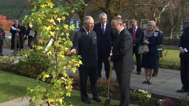 Уэльский секретарь Алан Кернс и первый министр Карвин Джонс наблюдают, как принц Чарльз сажает дерево в мемориальном саду Аберфана