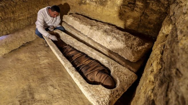 أثري مصري يفحص مومياء