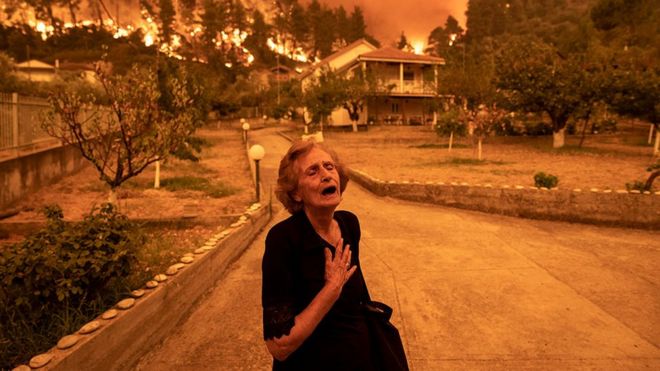 Una anciana grita cuando un incendio forestal se acerca a su casa en el pueblo de Gouves, en la isla de Evia, Grecia, el 8 de agosto de 2021.