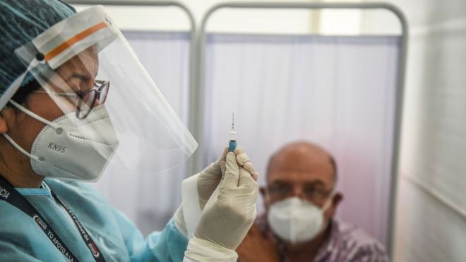Un trabajador de salud prepara una jeringa para ponerle la vacuna Sinopharm a un voluntario en la Universidad Peruana Cayetano Heredia en Lima, Perú.