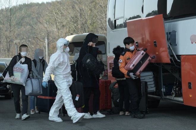 Пассажиры из Лондона загружают свой багаж в автобус после прохождения тестов на COVID-19 в отеле рядом с международным аэропортом Инчхон, в Инчхоне, Южная Корея, 23 марта 2020 года, чтобы их доставили на автобусе в центр для их двухнедельной изоляции.