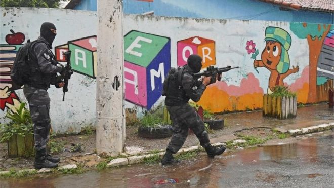 Дети наблюдают, как солдаты снимают контрольно-пропускной пункт, сделанный торговцами наркотиками возле фавелы Вила-Кеннеди в Рио-де-Жанейро, 23 февраля 2018 года.