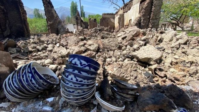 Some crockery is displayed near a home that has been reduced to rubble