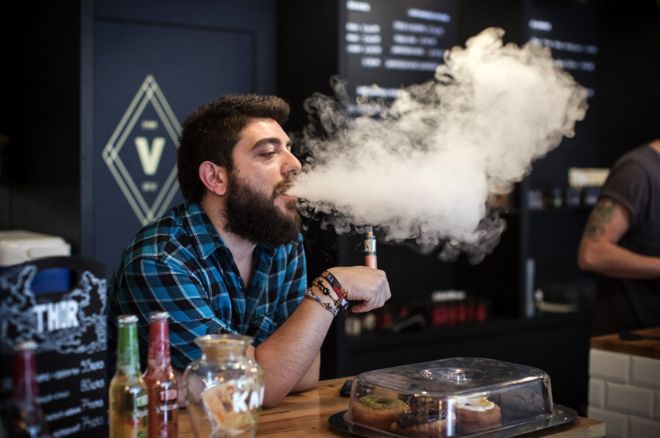 Сотрудник Vape Lab использует электронную сигарету во время работы