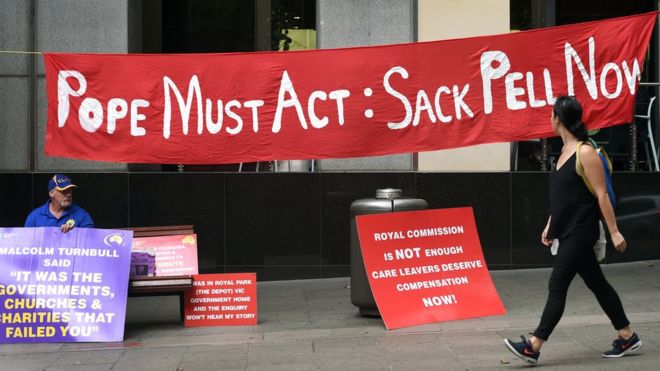 Протестующий за пределами Королевской комиссии держит плакат с плакатами об институциональных мерах по борьбе с сексуальным насилием над детьми в Сиднее