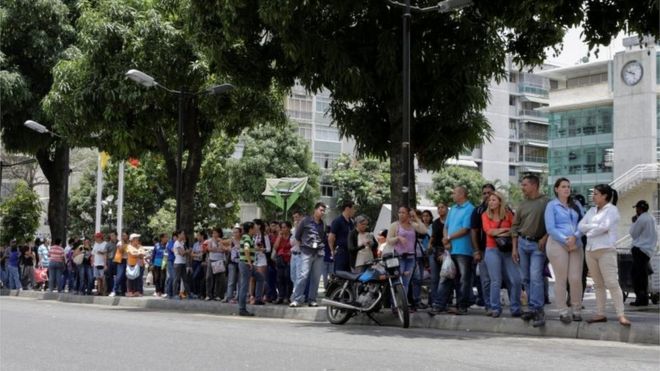 Люди стоят в очереди, чтобы попытаться купить основные продукты питания возле супермаркета в Каракасе, Венесуэла, 28 апреля 2016 года.