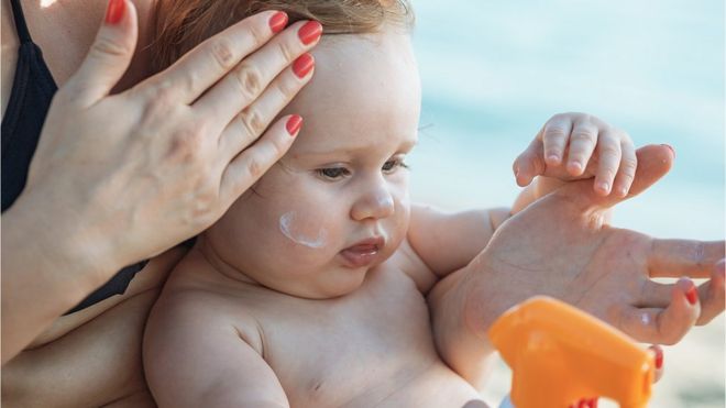 Мама наносит солнцезащитный крем ребенку