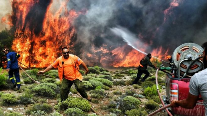 Imagem mostra quatro homens tentando controlar as chamas na maior onda de incêndios na Crécia em mais de uma década