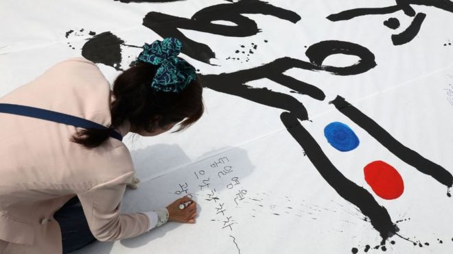 Южнокорейская женщина пишет сообщения доброй воли во время митинга, чтобы приветствовать предстоящий Межкорейский саммит