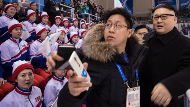 Некоторые болельщики неодобрительно смотрят на подражателя Ким Чен Ына, в то время как другие смотрят на хоккейный матч