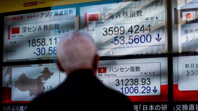 Чоловік у Токіо спостерігає за падінням фондових індексів