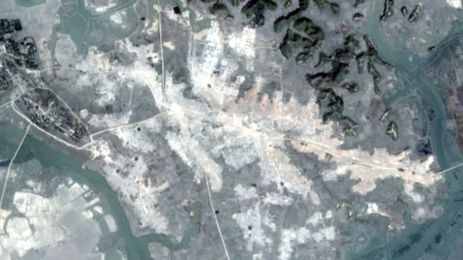 Спутниковое изображение показывает расположение деревни в ярко-белом - очевидно, бульдозерном грунте - в резком контрасте с зеленым ландшафтом вокруг него