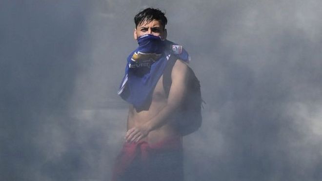 Joven emerge entre la humareda en las protestas en Chile.
