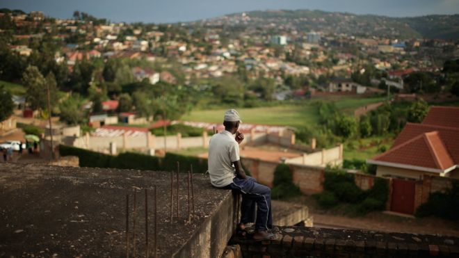 Мужчина сидит, когда вечернее солнце падает над районом Кикукиро столицы 5 апреля 2014 года в Кигали, Руанда.