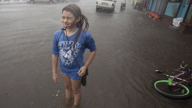 Una niña se moja bajo la lluvia.