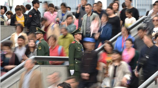Китайская военная полиция стоит на страже, когда люди посещают набережную на набережной