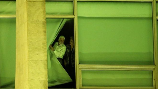 Президент Бразилии Дилма Руссефф в сопровождении начальника штаба Жака Вагнера смотрит из окна на дворец Планалто в Бразилиа, Бразилия, 11 мая 2016 года