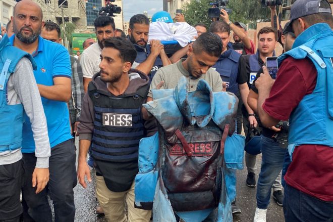 A colleague carries a blood-stained flak jacket belonging to Palestinian journalist Mohammed Soboh, who was killed along with two other journalists when an Israeli missile hit a building while they were outside reporting, at a hospital in Gaza City, 10 October 2023