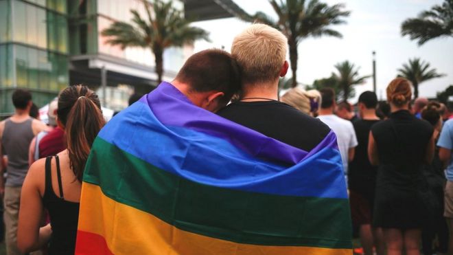 Dos hombres envueltos en una bandera del movimiento gay en Orlando, Florida