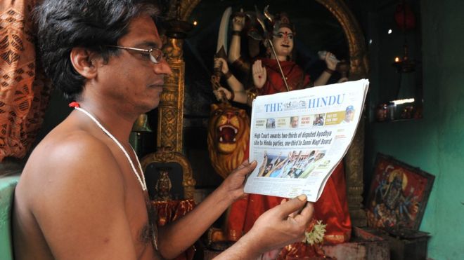 Индийский индусский священник Krishnama Charyulu читает газету с высоким приговором суда спорного дела Ayodhya внутри храма в Хайдарабаде на 1 октября 2010 года [[