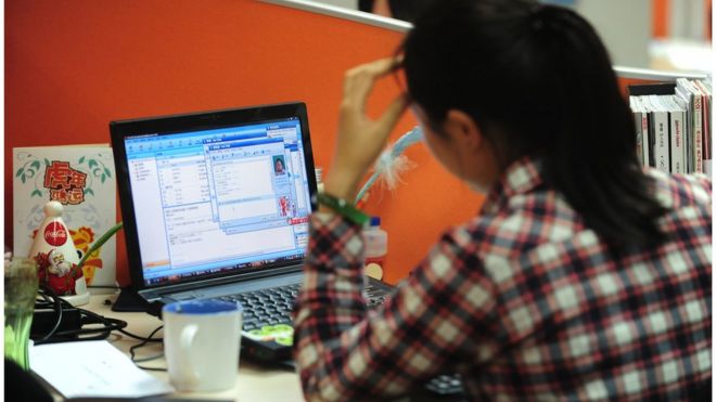 A woman works online in her cubicle at an office in Beijing