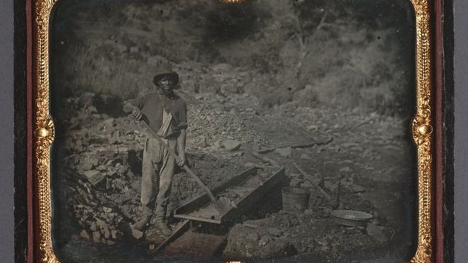 Foto mostra um homem negro não identificado trabalhando em uma mina de ouro em 1852