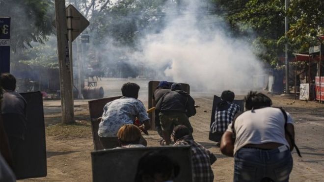 Protesters react after police fire teargas in Mandalay, Muanmar. Photo: 13 March 2021