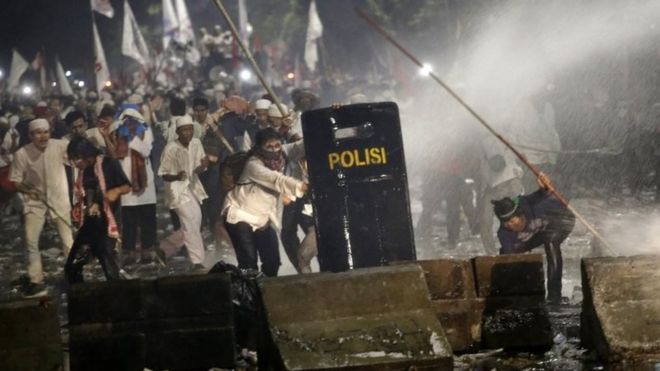 Протестующие опрыскивают водой из полицейского грузовика водометы во время столкновения возле президентского дворца в Джакарте, Индонезия, пятница, 4 ноября 2016 г.