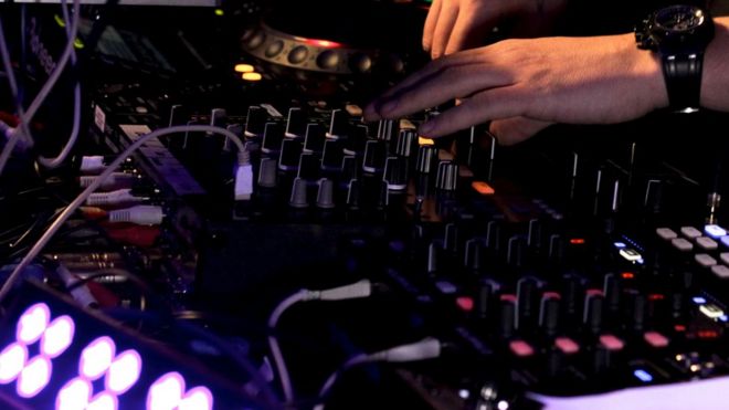 A DJ mixes dance music at a club