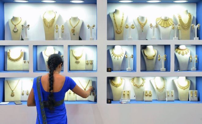 Сотрудник индийского ювелирного магазина организует золотые украшения в Бангалоре 11 августа 2017 года.