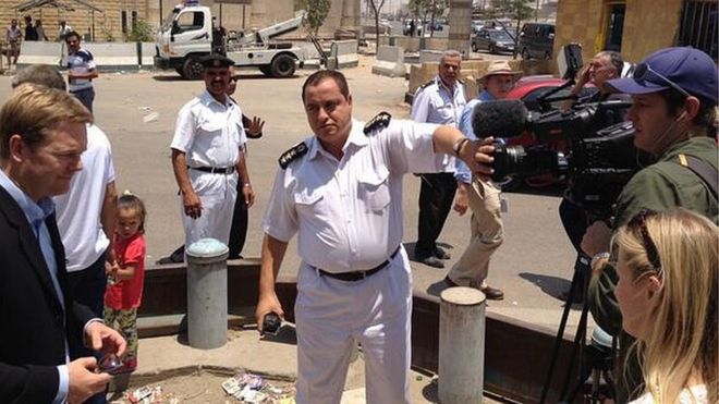 Египетский полицейский закрывает объектив камеры во время съемок фильма BBC за пределами тюрьмы Тора