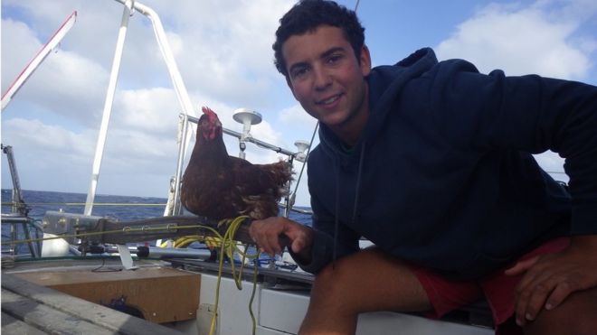 Матрос Гирек Суди держит курицу Моник на палубе яхты