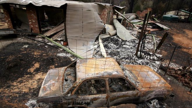Обгоревшие останки автомобиля и дома после лесного пожара в Кинглейке в Виктории