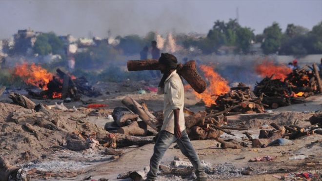 A crematorium worker carries wood for the cremation of victims who died from Covid-19 in Allahabad, India