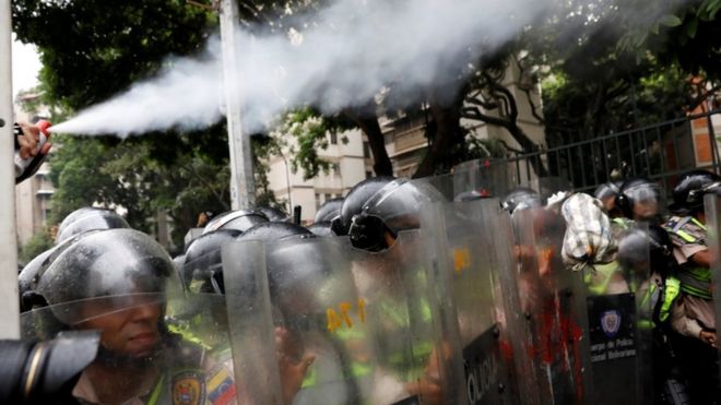Полицейский использует перцовый баллончик на марше в Каракасе