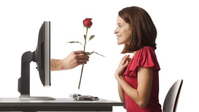 mujer recibiendo una rosa que sale de su computadora
