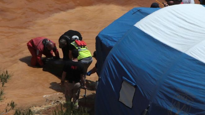 Судмедэксперты, спасатели и водолазы забирают чемодан, который, по словам полиции, содержит женское тело