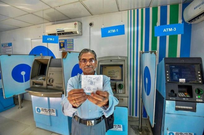 Мужчина демонстрирует квитанцию ??«без наличных» возле банкоматов SBI в Патне 17 апреля 2018 года. В большинстве банкоматов закончились наличные деньги в городе