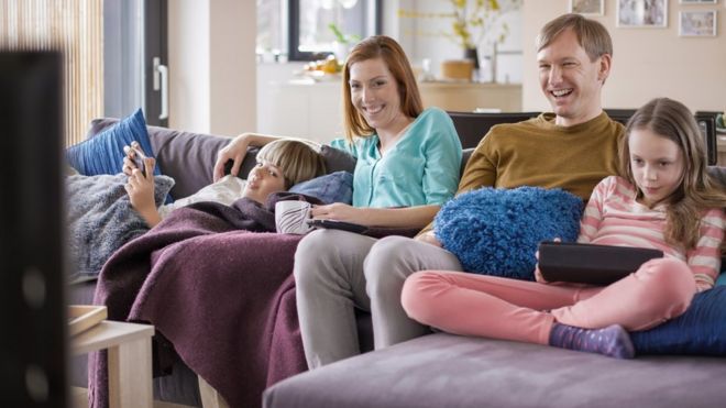 Семья на устройствах во время просмотра телевизора