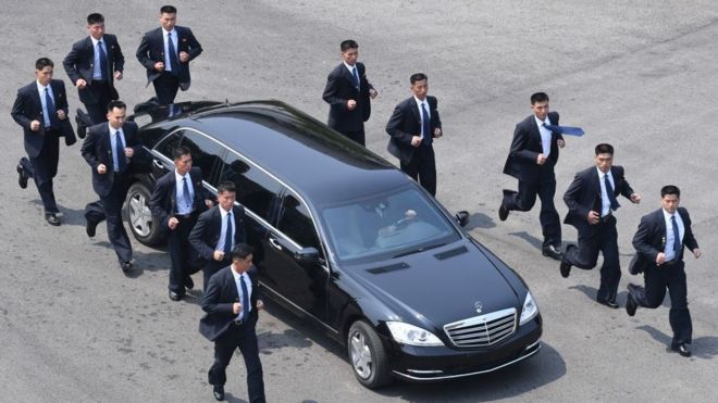 North Korean bodyguards jog next to a car carrying North Korea's leader Kim Jong Un
