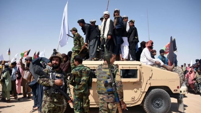 Боевики и жители афганских талибов стоят на бронированном автомобиле "Хамви" Афганской национальной армии, когда они празднуют перемирие в третий день Ид в округе Майванд провинции Кандагар