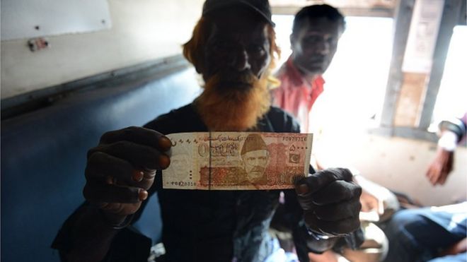 Indian fisherman displays a 5000 Pakistani rupee note