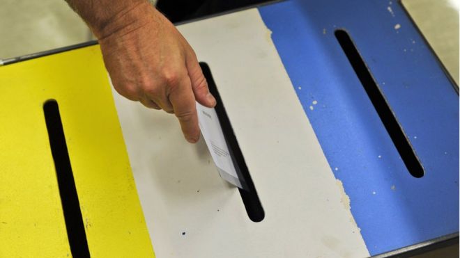 Избиратель кладет свою бумагу в урну для голосования