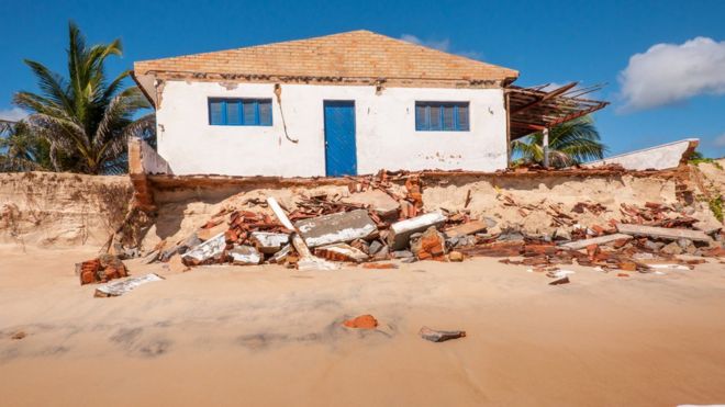 Foto da praia de Pititinga, em Natal, onde o avanço do mar diminuiu a faixa de areia e engoliu construções.