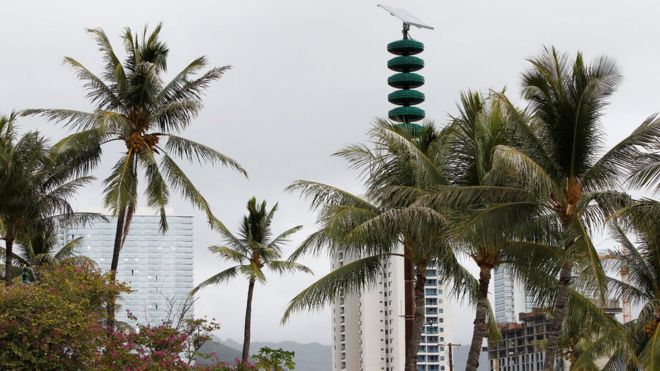 A tsunami warning tower in between palm trees at Kakaako Waterfront Park in Honolulu, Hawaii, November 28, 2017