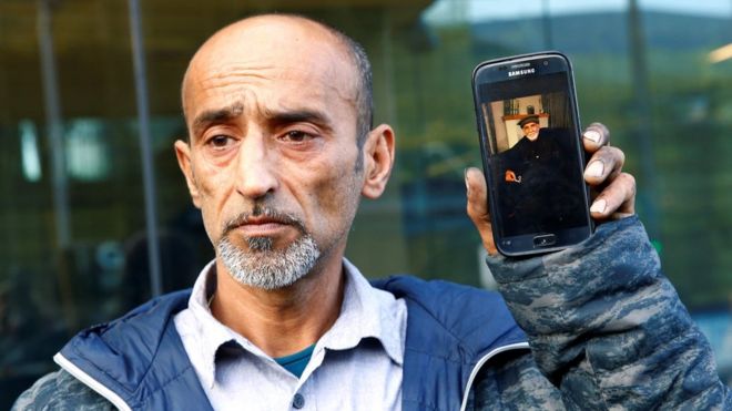 Омар Наби держит телефон с фотографией своего отца Дауда, который погиб в расстреле мечети Крайстчерч (16 марта)