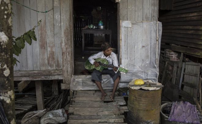 Человек играет на гитаре в своем доме в Хинтаде